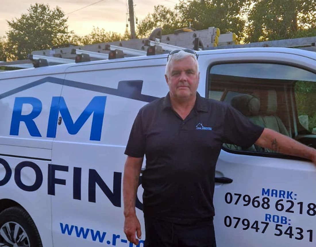 Mark Hutchings beside a branded RM Roofing van at sunset in Neath