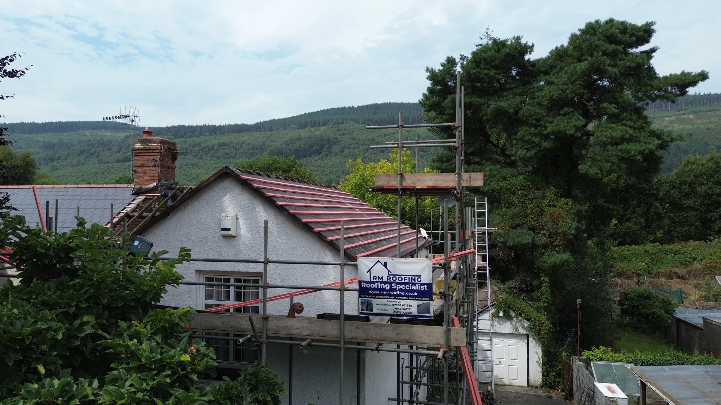 Roof strip and re-roof in progress with RM Roofing banner, Neath